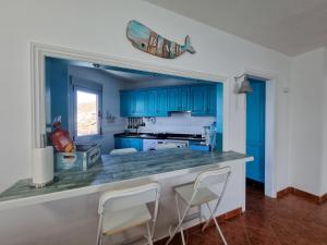 a kitchen with blue cabinets and a counter with chairs at Apartment on the sea in Puerto de la Madera