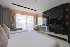 um quarto com uma grande cama branca e uma televisão em Patong Beachfront Studio 2 Mins Walk 2 Patong Beach em Praia de Patong