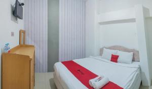 een slaapkamer met een wit bed en een rode deken bij RedDoorz Syariah at Jemursari Surabaya in Surabaya