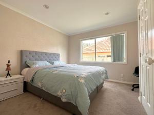 sypialnia z dużym łóżkiem i oknem w obiekcie Cheerful 4 bedrooms home with stunning sunshine w Auckland