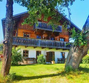 una gran casa de madera con un árbol delante en Landhaus Friedl, en Riedlhütte