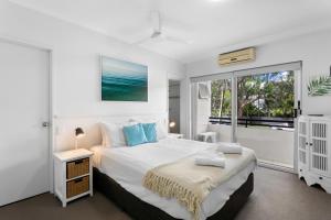 a white bedroom with a bed and a window at Riviera Noosa Resort in Noosaville