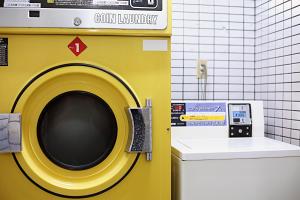 a yellow washing machine in a bathroom next to a toilet at Asakusa nibankan in Tokyo