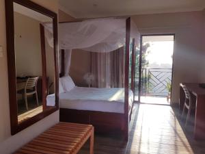 - une chambre avec un lit avec un miroir et un balcon dans l'établissement Chinyonga Guesthouse, à Limbe