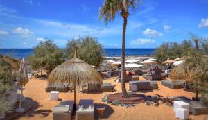 einen Strand mit Liegestühlen und Sonnenschirmen und einer Palme in der Unterkunft Luxury House Paraiso Del Palm Mar in Palm-mar