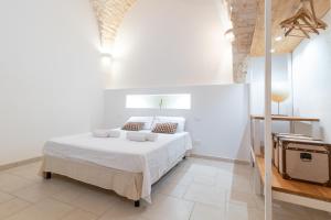een witte slaapkamer met een bed met witte lakens en kussens bij Casa Maestra in Ceglie Messapica