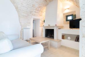 een woonkamer met een witte bank en een open haard bij Casa Maestra in Ceglie Messapica