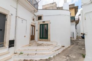 een wit gebouw met een trap en een groene deur bij Casa Maestra in Ceglie Messapica