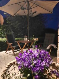 einen Regenschirm und einen Tisch und ein paar lila Blumen. in der Unterkunft Lütje Huus in Upgant-Schott