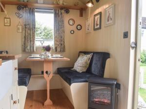 Shepards Hut في Frampton on Severn: منزل صغير مع مقعد وطاولة وموقد