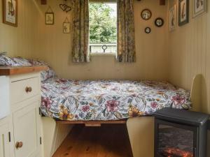 Shepards Hut في Frampton on Severn: سرير صغير في غرفة مع نافذة
