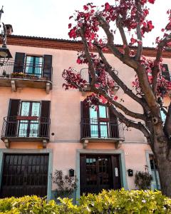 un bâtiment rose avec des fenêtres et un arbre avec des fleurs roses dans l'établissement Casa Clementi, à Barolo