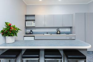 a kitchen with white cabinets and a table with stools at Aubyn Court Spa Motel in Palmerston North