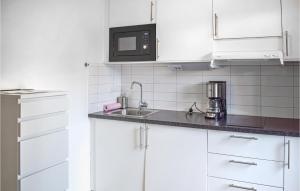 a white kitchen with a sink and a microwave at Wasa Seaside 2 in Färjestaden
