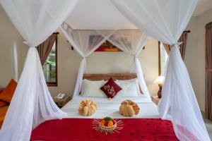 a bedroom with a bed with white drapes at Kiskenda Cottages & Restaurant in Ubud