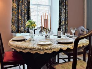 a dining room table with chairs and a table with plates and glasses at Sanderling End in Lowick