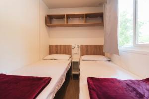 2 łóżka w małym pokoju z oknem w obiekcie Camping Nuovo w mieście Massa