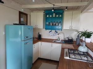 een keuken met een blauwe koelkast en witte kasten bij Ojcowski Zakątek-uroczy domek do wynajęcia in Wola Kalinowska