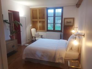 1 dormitorio con cama blanca y ventana en La Ferme au colombier, en NÃ©ron