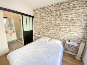 1 dormitorio con pared de ladrillo y cama blanca en Le Rémois - PARKING - Cour privative - WIFI, en Reims