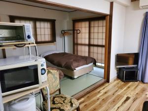 Habitación hospitalaria con cama y TV en Hakuba Inn Bloom en Hakuba