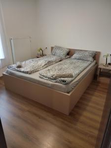 a bed in a bedroom with a wooden floor at Tiszaliget Apartman és Szálló in Szolnok