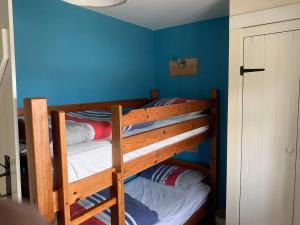2 łóżka piętrowe w pokoju z niebieskimi ścianami w obiekcie The Hayloft w mieście Bude