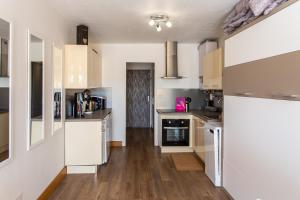 kuchnia z białymi szafkami i drewnianą podłogą w obiekcie Cocooning w Cap d'Agde +5 zdjęć