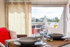 uma mesa com copos e pratos com uma janela em Cocooning em Cap d'Agde