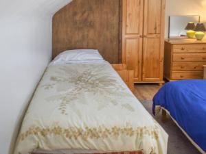 a bedroom with a bed and a wooden headboard at 20 Blackbird Cottage-uk38935 in Porthcurno