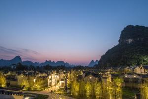 a city lit up at night with mountains in the background at Banyan Tree Yangshuo in Yangshuo