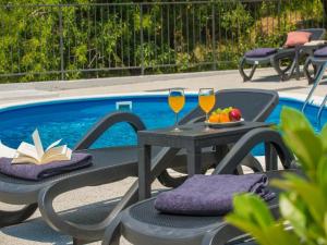 stół i krzesła z kieliszkami do wina przy basenie w obiekcie Holiday Home Nest w mieście Mlini