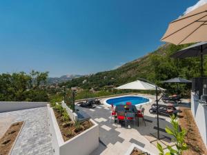 a patio with a pool and tables and an umbrella at Family Holiday Home Nest in Mlini