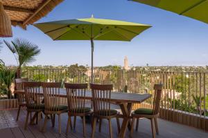 una mesa y sillas con una sombrilla en la cubierta en Hotel Jadali & Spa, en Marrakech