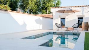 een zwembad met 2 stoelen en een parasol naast een huis bij Acogedora casa de invitados con piscina compartida in Toledo