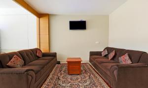 a living room with two brown couches and a tv at Itsy By Treebo - Kottaram Residency in Ooty