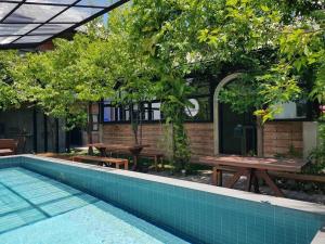a swimming pool with tables and benches next to a building at The Wishes Hotel at Chiangmai in Chiang Mai