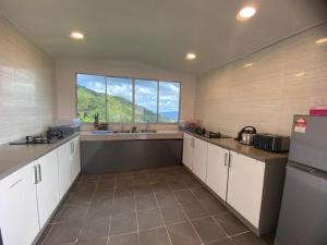 a kitchen with white cabinets and a large window at Bayu Senja Lodge in Kampong Kundassan