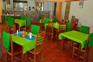 Gorilla Hills Eco-lodge في Kisoro: غرفة طعام مع طاولات وكراسي خضراء