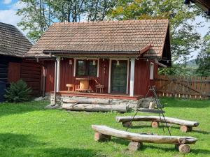 a small red cabin with a porch and a table at Siedlisko na Groniku in Kokuszka