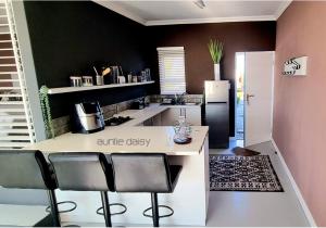 a kitchen with a counter with chairs and a refrigerator at The Lazy Daisies in St Helena Bay