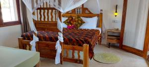 a bedroom with a wooden bed with a canopy at Namayani apartment in Pwani Mchangani