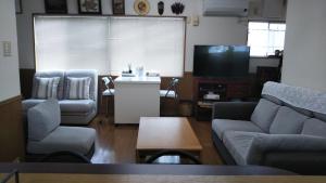 sala de estar con sofá, mesa y TV en ゲストハウス小富士 en Oita