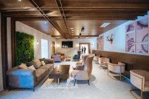 a living room with a couch and tables and chairs at Hotel Rajska dolina Jahorina in Jahorina