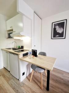 a kitchen with a wooden table and a counter top at La Studieuse - Hyper centre ville in Noisy-le-Grand