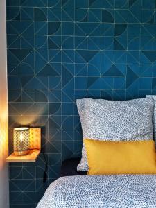 a blue tiled bedroom with a bed and a yellow pillow at La Studieuse - Hyper centre ville in Noisy-le-Grand