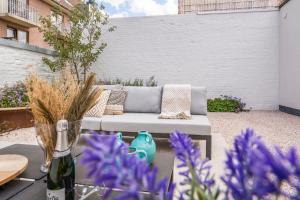 a patio with a couch and some purple flowers at Maison Odett - fully renovated house for 10 people in Nieuwpoort