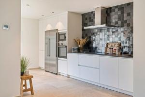 eine Küche mit weißen Schränken und Geräten aus Edelstahl in der Unterkunft Maison Odett - fully renovated house for 10 people in Nieuwpoort + 29 Fotos