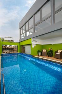 una gran piscina en un edificio con paredes verdes en Nesta Hotel Saigon, en Ho Chi Minh