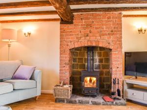 a living room with a brick fireplace with a tv at Hollywell Cottages in Clifton
